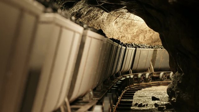 Coal mine carts or wagons slowly moving through narrow underground tunnel.
