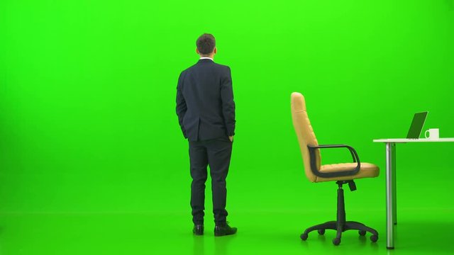 The businessman relaxing at the table on the green background