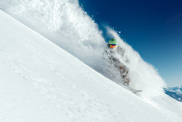 man snowboarder is going very fast in   stream of snow avalanche