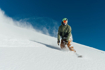 Fototapeta na wymiar snowboarder in gear brakes on slope freeride brakes creating a wave of snow