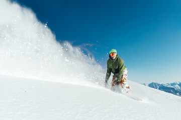 male snowboarder curved and brakes spraying loose deep snow on  freeride slope