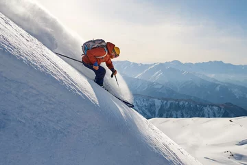 Rolgordijnen skier rides freeride on powder snow down slope against the backdrop of the mountains © Аrtranq