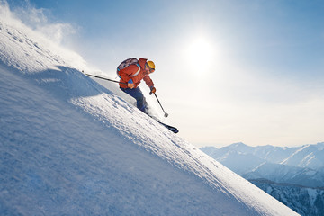 skier rides freeride on powder snow down slope against the backdrop of the mountains - obrazy, fototapety, plakaty