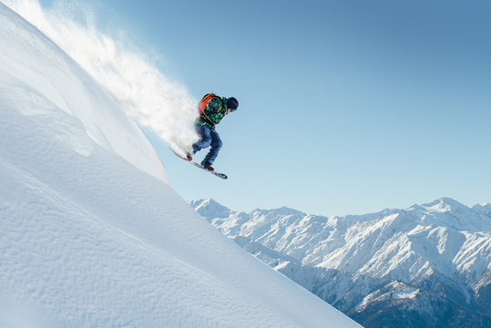 snowboarder jumping on steep mountainside