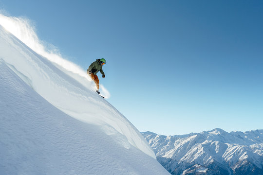 snowboarder rides on steep mountainside on a beautiful landscape