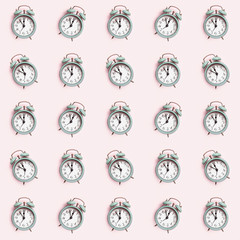 Seamless pattern with retro style alarm clock over the pastel pink background