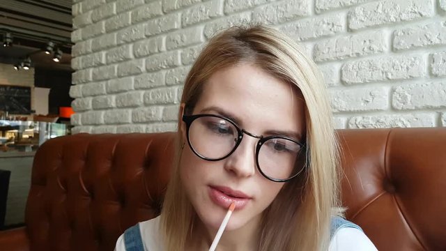 Woman applying natural lips glance in cafe.