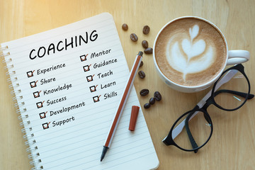 coaching and check list marks in notebook with glasses, pencil and coffee cup on wooden table. Project management concept. - obrazy, fototapety, plakaty