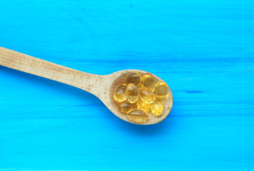 Fish fat in spoon on blue background.