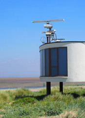 the old coastguard station in fleetwood with radar antennae with crass covered dunes leading to the beach on a summers day in bright sunlight with blue sky