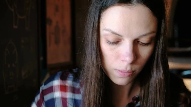 Closeup woman's face eating a piece of pork using a fork. Tired woman have a dinner.