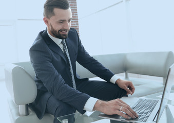 Smiling businessman browsing information on laptop,