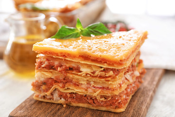 Portion of tasty lasagna on wooden board