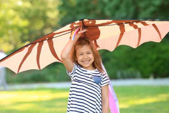 Cute little girl playing with kite outdoors