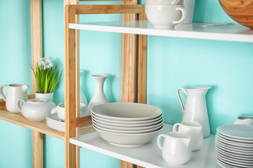 Kitchen shelving with dishes on color wall background