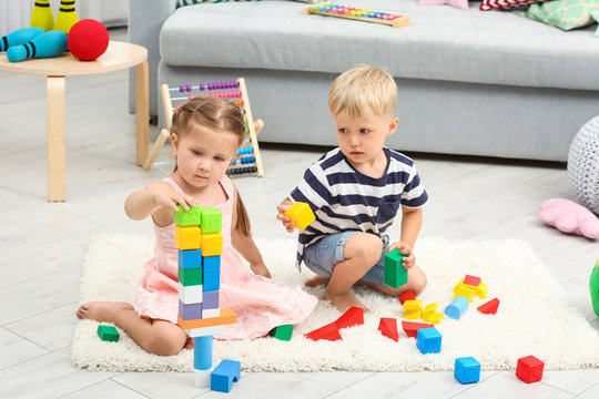 Cute children playing with constructor on floor at home