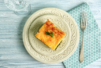 Plate with piece of tasty spinach lasagna on wooden table