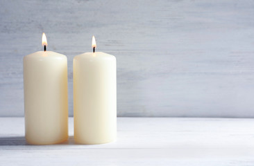 Fototapeta na wymiar Beautiful burning wax candles on table against light background