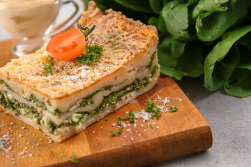 Lasagna with spinach on wooden board, close up