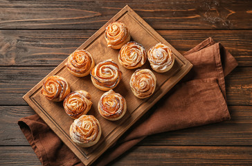 Wooden board with apple roses from puff pastry on table