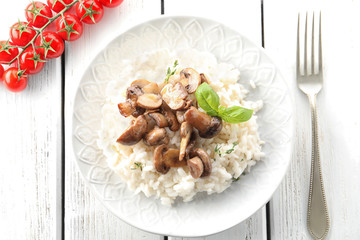 Plate with delicious risotto and mushrooms on wooden table