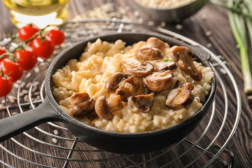 Frying pan with risotto and mushrooms on wooden table