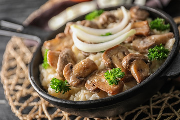 Frying pan with risotto and mushrooms on table, closeup