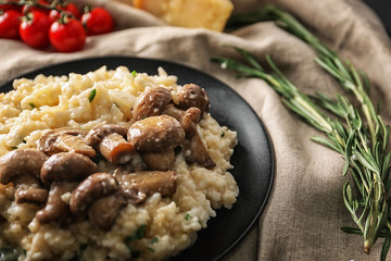 Plate with risotto and mushrooms on table, closeup