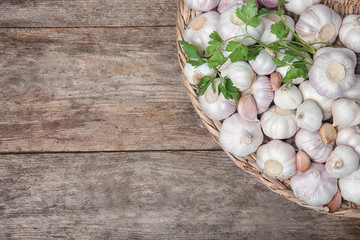 Wicker plate with fresh garlic on wooden background, top view