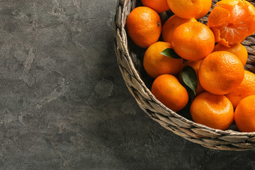 Wicker basket with juicy tangerines on table