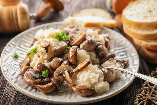 Plate with risotto and mushrooms on wooden table, closeup