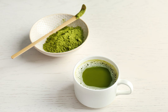 Cup of fresh beverage and chawan with powdered matcha tea on table