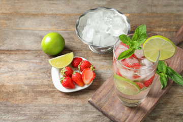 Glass of natural lemonade with lime, strawberries and mint on table