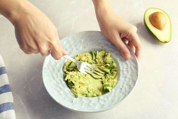 Woman preparing guacamole of ripe avocados at table