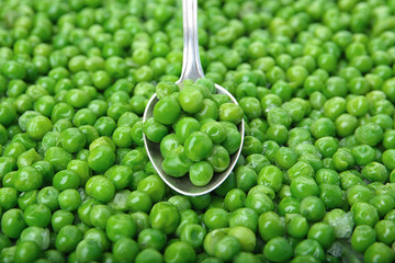 Frozen peas and spoon, closeup. Vegetable preservation