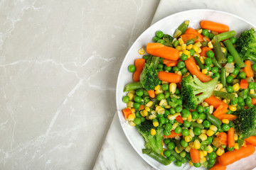 Plate with mix of frozen vegetables on light background, top view
