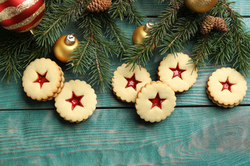 Linzer cookies with sweet jam and Christmas decorations on wooden background, top view