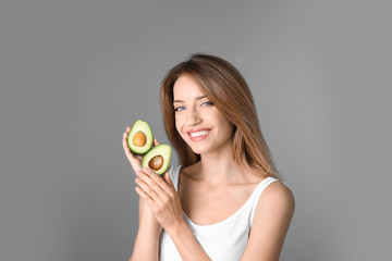 Portrait of young beautiful woman with ripe delicious avocado on color background