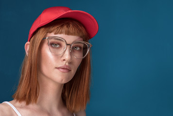 Fashionable redhead girl in red cap and eyeglasses.