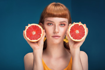 Girl with grapefruit on blue background.