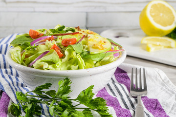 Delicious vegetable salad with apple slices  in white ceramic bowl on table.