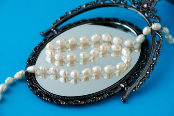 Pearl beads on the mirror. Jewelry in the form of pearl beads. Bijouterie is reflected in the mirror.