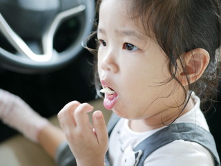 Little Asian baby girl, 24 months old, is choking while eating a piece of apple