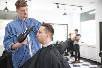 Professional barber working with client in hairdressing salon. Hipster fashion