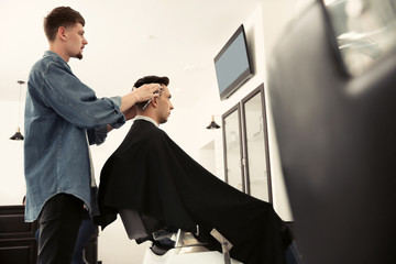 Professional barber working with client in hairdressing salon. Hipster fashion