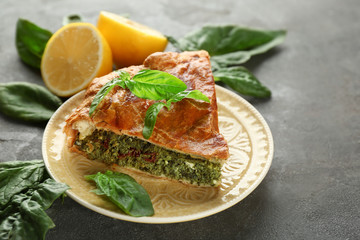 Piece of tasty pie with spinach on plate