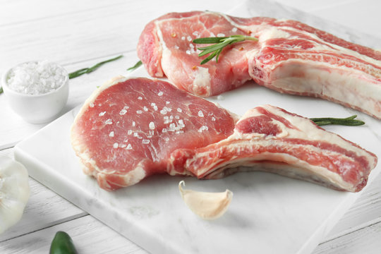 Marble board with fresh raw pork ribs on wooden table