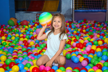 Fototapeta na wymiar Cute girl playing among plastic balls