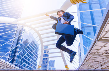 A young Asian businessman in town. A man jump in to sky. He is happy and gleeful. Portrait, Handsome, Bangkok, Thailand. Photo businessman and good feel concept.