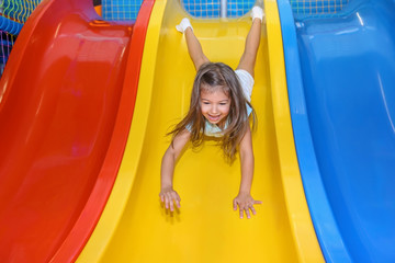 Little girl riding on slide in entertainment center